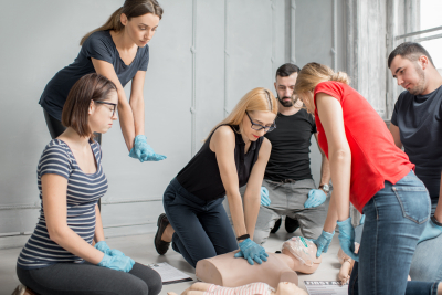 Group of people learning how to make first aid heart compressions