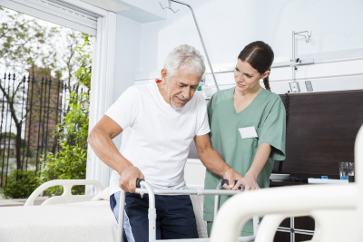 Nurse helping old man using walker